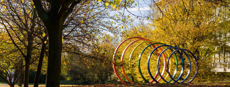 TU Dortmund im Herbst Spektralringe aus Stahl umgeben von Bäumen im Herbst.